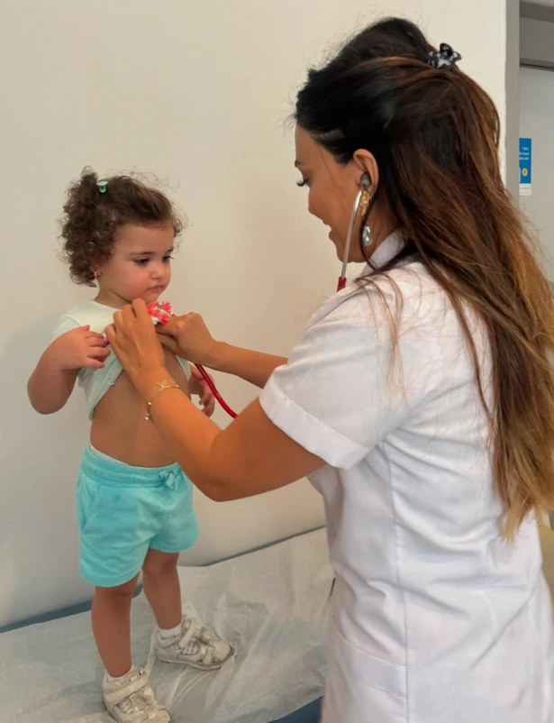 Uzman pediatr Gülnar Nəcəfova azyaşlı uşağı stetoskopla müayinə edir